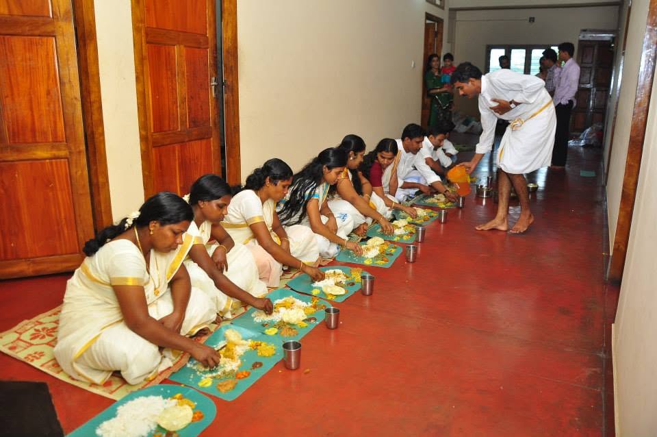 Guests seated in a row for the community meal, each with a leaf set before them