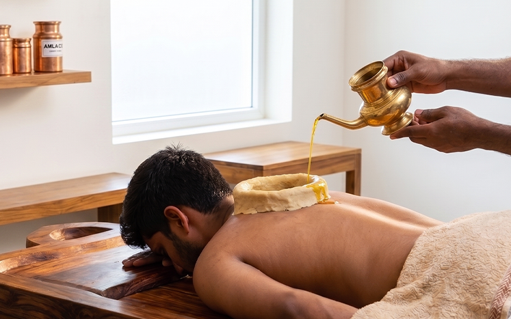 A dough ring holding warm oil over a patient's lower back